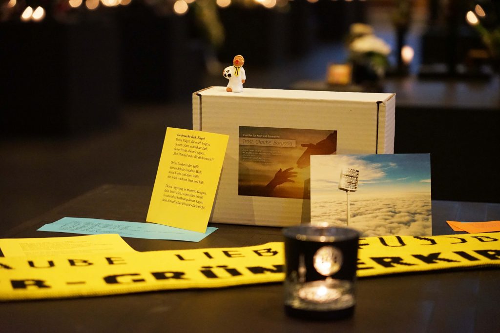 Die Trauerbox mit der Aufschrift „Trost – Glaube – Borussia“ enthält bewusst ausgewählte Elemente, darunter ein Windlicht oder eine Kerze als Zeichen der Erinnerung, ein kleiner Engel als Symbol von Schutz und Nähe, Trost- und Hoffnungstexte aus christlicher und literarischer Tradition sowie ein persönliches Anschreiben der BVB-Gründerkirche. Foto: Michael Bodin / Erzbistum Paderborn